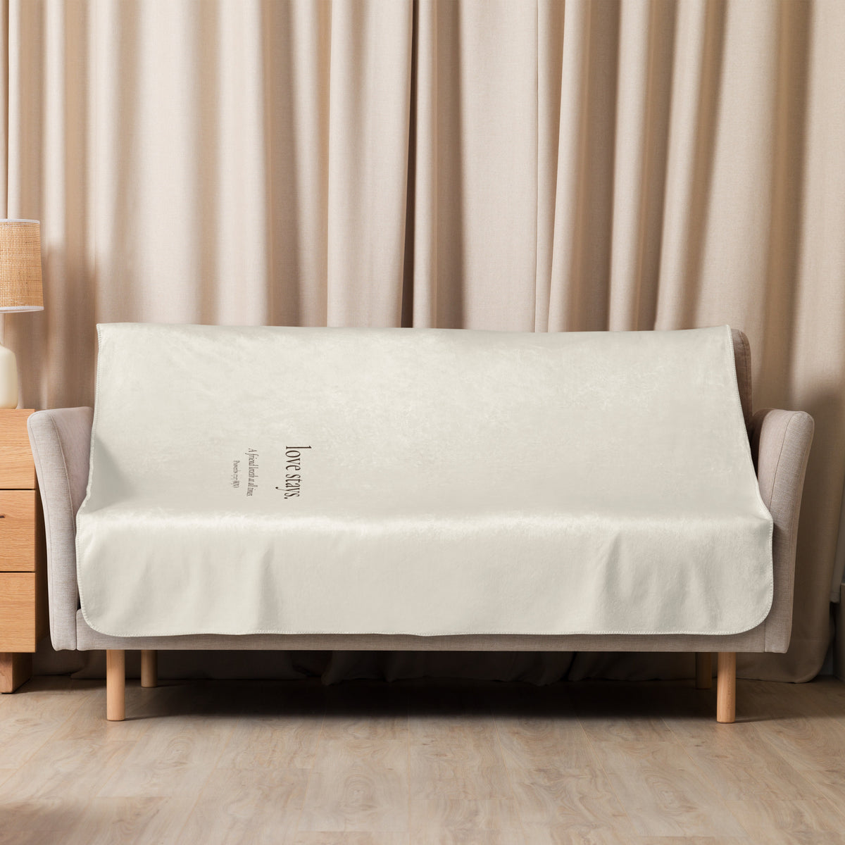 A cream love stays. velveteen blanket draped over a sofa in a warm, quiet room.