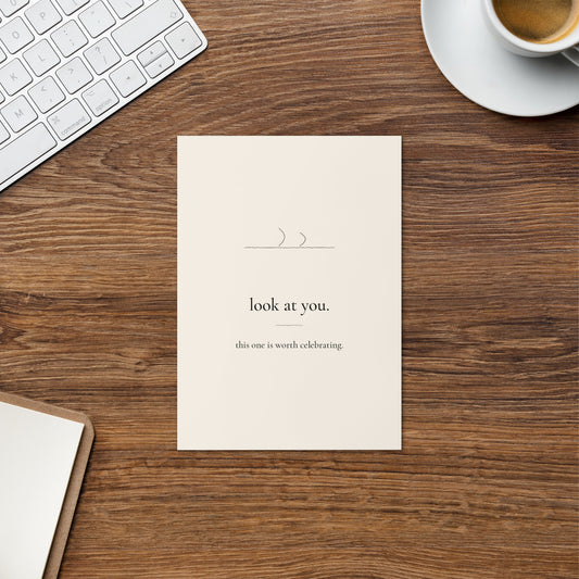 Look at You card on a warm wood desk beside a cup of coffee and a keyboard.