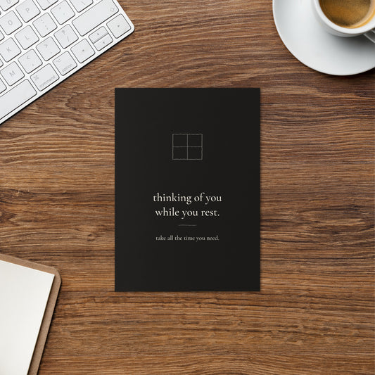 Thinking of You While You Rest card on a warm wood desk beside a cup of coffee and a keyboard.