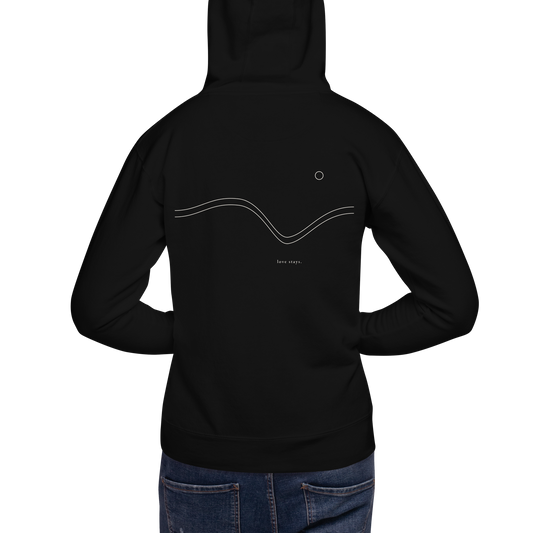Person wearing the black love stays. The Held Line Hoodie, back view showing the cream Held Line drawing of two lines through a valley